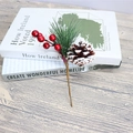 Rama de pino navideño con bayas rojas y piña nevada sobre libros decorativos - Adorno de Piña Pintada de Blanco 18cm