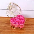 Close-up of six pink soap roses in a golden heart-shaped wire basket on wood - Rose Red