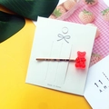 Close-up of a red jelly bear hair clip on a decorative card with a gold metal base - Red