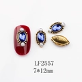 Macro detail of oval blue gemstone nail art charm with gold base and white pearls - 2557 Royal Blue