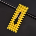 Detail shot of yellow bubble texture hair clip with golden metal base on dark surface - Yellow Rectangle