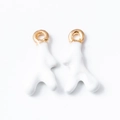 Dettaglio macro di orecchini astratti in smalto bianco con ganci in metallo dorato - Beige