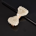 Detailed view of pearl woven bow hair clip with gold metal clasp on reflective surface - Small Pearl Bow
