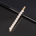 Close-up of gold metal hair clip featuring evenly arranged white pearls on a black surface - Large Pearl Beaded Flat Bobby Pin