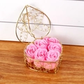 Detail of pink soap roses inside a heart-shaped golden wire basket on wooden surface - Pink