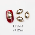 Macro shot of 7x12mm vintage gold oval nail charm with crystal inlay and small rhinestones - 2544 White