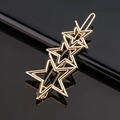 Vue détaillée de la barrette à cheveux dorée en forme d'étoile sur fond noir brillant - 3 étoiles creuses
