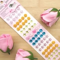 Bunte 3D-Kristallaufkleber mit Herzen und Sternen auf einem hölzernen Hintergrund - Blume Gold