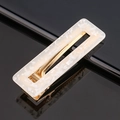 Détail macro d'une barrette rectangulaire en acétate blanc avec mécanisme à ressort doré - Paillettes blanches carré