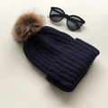Dark blue knitted beanie for women featuring a large brown faux fur pom pom detail - Navy Blue