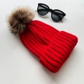 Winter red knitted beanie for women featuring a large brown faux fur pom pom - Red