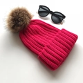 Rose red knit beanie with a brown faux fur pom pom shown in a flat lay view - Rose Red