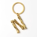 Detailed close-up of golden metal letter N keychain featuring a textured branch design - Letter N