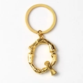 Detail of golden Q-letter keychain with a unique bone-like textured metal design - Letter Q
