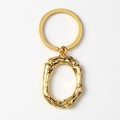 Detailed view of gold alloy letter O keychain with unique branch texture on white background - Letter O