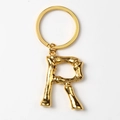 Detailed close-up of golden metal letter R keychain with unique bamboo texture - Letter R