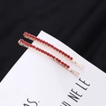 Vue détaillée de deux barrettes dorées avec des strass rouges brillants sur une carte - Lot de 2 / Rouge