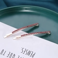 Detailed close-up of two silver hairpins with pink rhinestones on green ceramic - 2Pcs/Set / Pink