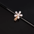 Close-up of golden floral hair clip with inlaid white pearls on a reflective black base - Single Plum Blossom