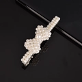 Macro shot of white pearls arranged in a bow shape on a silver metal duckbill clip - Cupid Bowknot Hair Clip