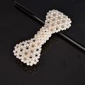 Detail of a white pearl-woven bow hair clip showing elegant beadwork on a reflective surface - Wrapped Bowknot