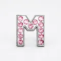 Close-up of a silver letter M charm slider with sparkling inlaid pink rhinestones - Pink - Letter M