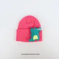 Detailansicht der rosaroten Strickmütze mit grünem 3D Cartoon Dinosaurier Stickaufnäher - Cartoon Dinosaurier / Dunkelrosa
