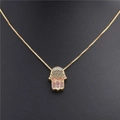 Detail van gouden Hamsa hand hanger met regenboog zirkonia op een zwarte display mannequin - Hand van Fatima