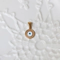 Macro view of a round 18K gold evil eye pendant with blue enamel and textured gold border - G10-Enamel Evil Eye
