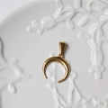 Detailed macro view of an 18K gold-plated crescent moon pendant on a ceramic tray - G01-Inverted Crescent Moon