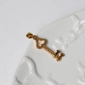 Detailed view of an 18K gold-plated key pendant on a vintage white ceramic tray - G16-Clover Key