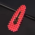 Detail view of coral pink pearl hair clip with textured beads on a black reflective surface - Watermelon Red Waterdrop