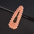 Close-up of a pink beaded rectangular hair clip with a metal spring base on black background - Peach Waterdrop