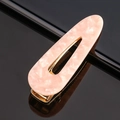 Détail de la pince à cheveux en acétate marbre rose avec base dorée et design ovale ajouré - Acétate rose goutte d'eau