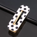 Detail view of the black polka dot acetate hair clip with a gold metallic frame - Black Polka Dot Square