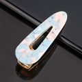 Détail macro d'une barrette en acétate marbré bleu ciel avec base en métal doré - Acétate bleu lac goutte d'eau