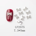 Détails macro de nœuds argentés pour ongles avec strass sur une manucure rouge foncé - Nœud Argenté Pavé de Strass Blancs (LF2575)