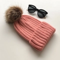 Pink knitted beanie hat featuring a large brown faux fur pompom and ribbed texture - Pink