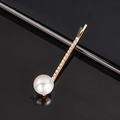 Elegant gold wavy hair clip featuring a glossy white pearl on a reflective dark base - Pearl Twist Bobby Pin
