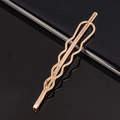 Minimalist rose gold metal bobby pin with wave design on black reflective background - Wave Tapered Metal Bobby Pin