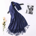 Detail of dark blue cashmere scarf with dense tassels and material label on wooden hanger - Navy Blue