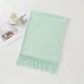 Pale green cashmere-feel scarf with fringes laid next to a coffee cup and magazine - Cyan