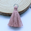 Dusty pink cotton tassel pendant with silver metal ring on a rustic wood background - Dark Apricot