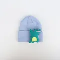 Detail einer hellblauen Strickmütze mit strukturiertem 3D-Dinosaurier-Patch in Grün - Cartoon Dinosaurier / Himmelblau