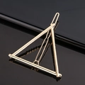 Minimalist gold triangle metal hair clip shown on a black reflective mirror surface - Triangle / Gold