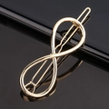 Vue macro d'une pince à cheveux dorée à motif infini avec finition métallique polie - Infini