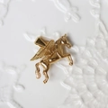 Macro shot of 18K gold plated Pegasus pendant with detailed wings on white surface - G12-3D Unicorn/Pegasus