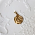 Vista dettagliata del ciondolo a rosa in oro 18K con rilievo 3D su un piatto di ceramica - G13-Rosa Rotonda