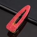 Détail de la pince à cheveux en acétate rouge marbré avec base en métal doré chic - Paillettes rouges goutte d'eau
