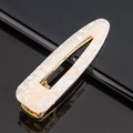 Macro d'une pince à cheveux en acétate marbre blanc avec base en métal doré sur noir - Paillettes blanches goutte d'eau